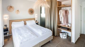 Una habitación de hotel moderna con una cama grande, un armario y una zona de tocador.
