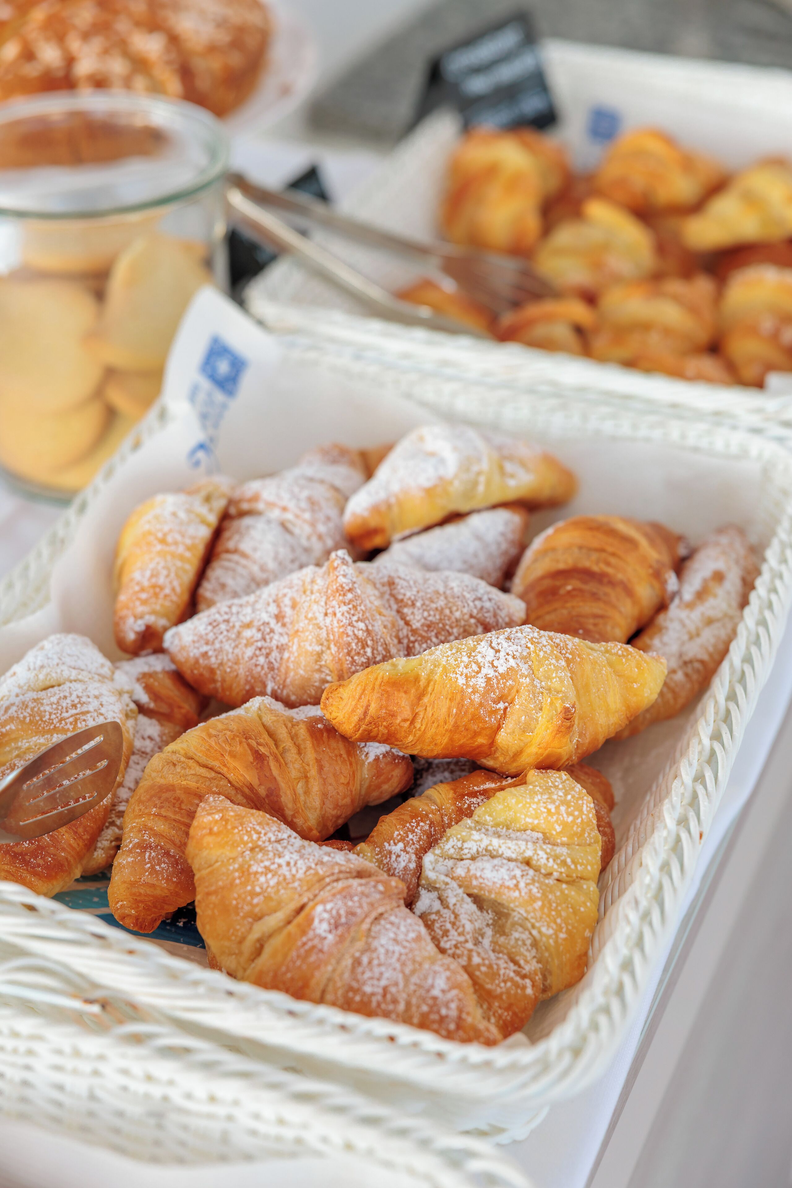 Une variété de viennoiseries, notamment des croissants et d’autres produits de boulangerie, présentées dans un panier.