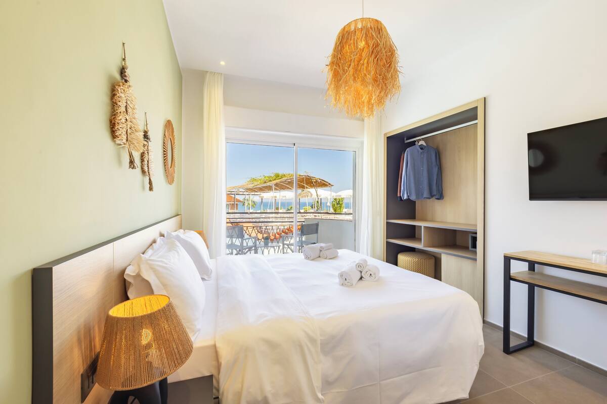 Habitación de hotel con cama, lámpara de noche, televisión y vistas al exterior.
