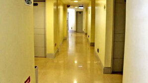 Un long couloir étroit d’hôtel, avec des portes des deux côtés et un panneau indiquant une sortie.