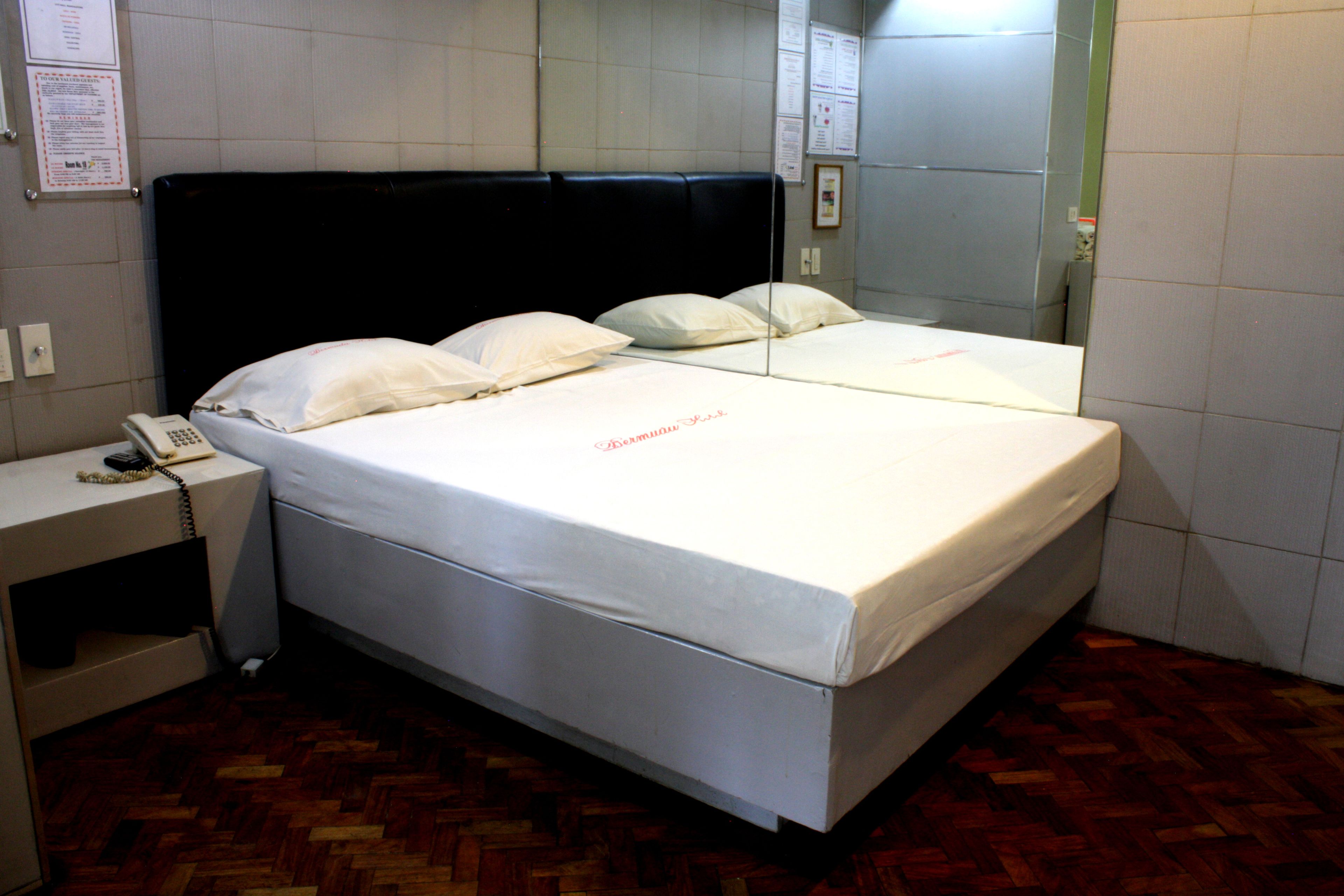 Habitación de hotel con cama, mesita de noche y espejo.