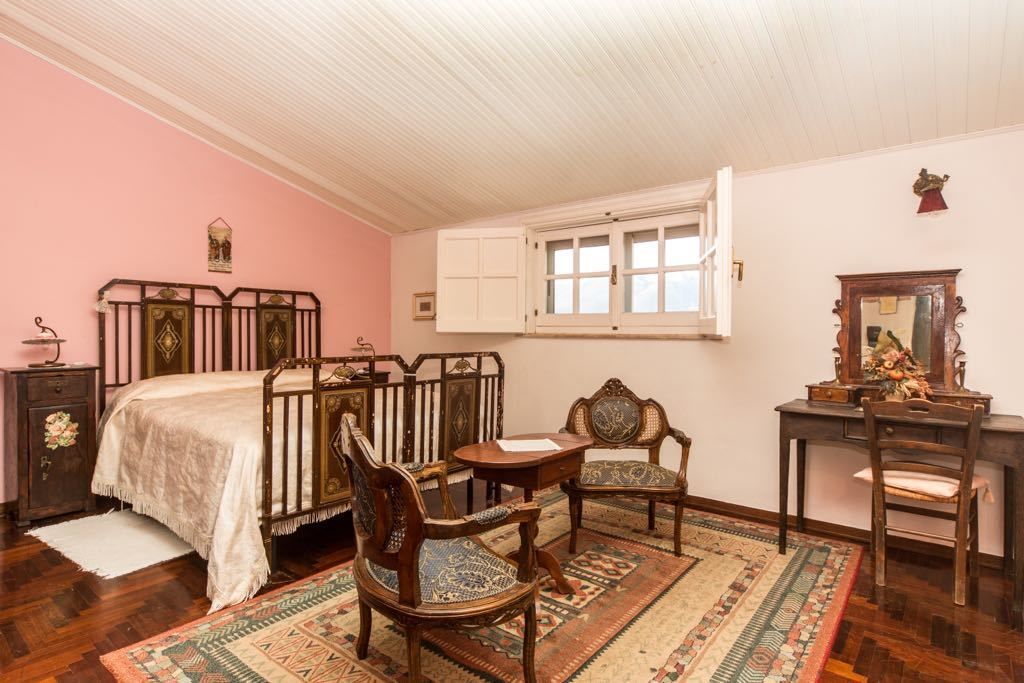 A bedroom with a bed, two chairs, a desk, and a mirror.