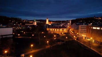 Vista nocturna de un pueblo con edificios iluminados y una torre de iglesia destacada.