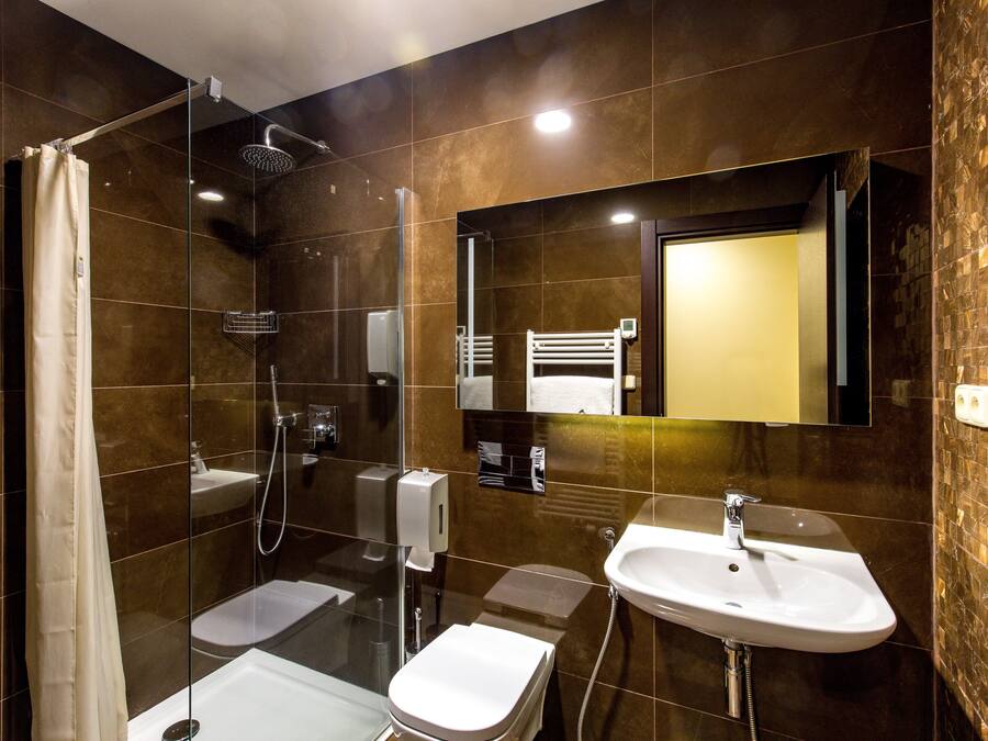 A modern bathroom with a glass-enclosed shower, a white toilet, and a sink with a mirror above it.