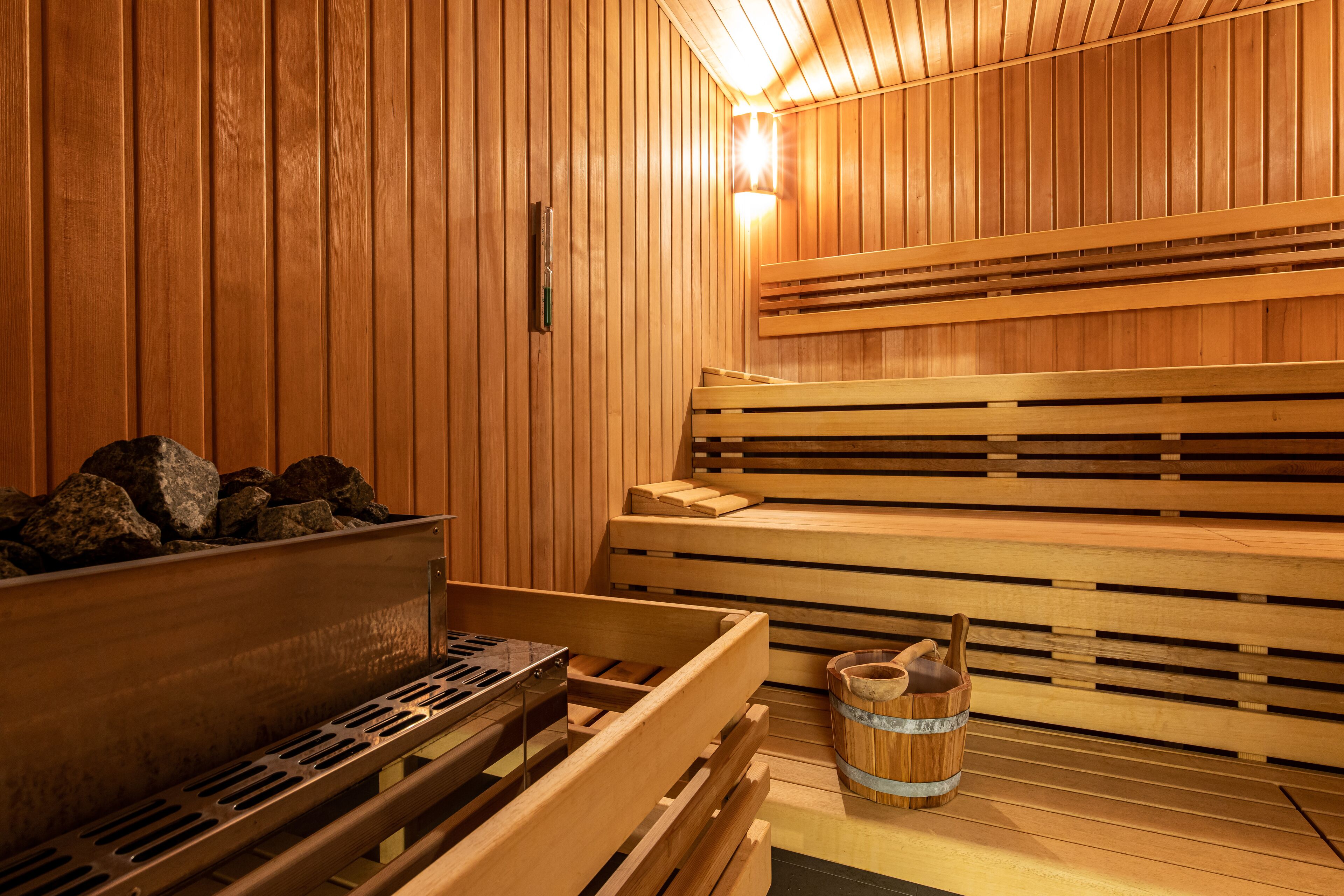 Una sauna de fusta amb bancs i una banyera de pedra.