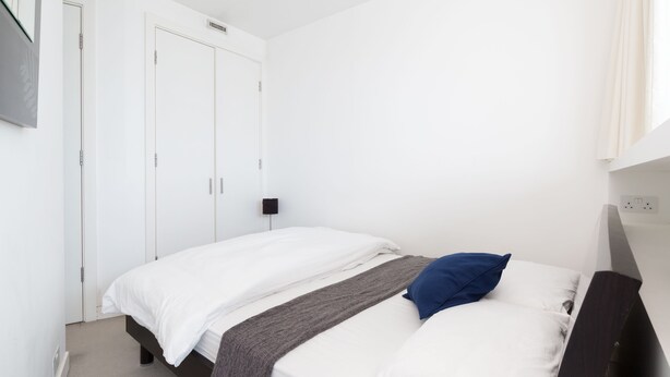 Un dormitorio sencillo y limpio con cama, mesita de noche y armario.