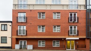 Un edificio residencial de varios pisos con fachada de ladrillo, múltiples ventanas y balcones.