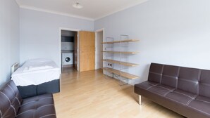 Una habitación moderna con cama, un sofá de cuero marrón y una estantería empotrada.