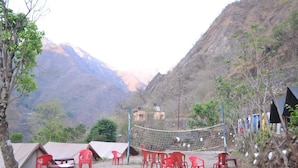 A mountainous area with tents and red plastic chairs arranged for outdoor activities. - Camp Eagle Nest (Narendranagar)