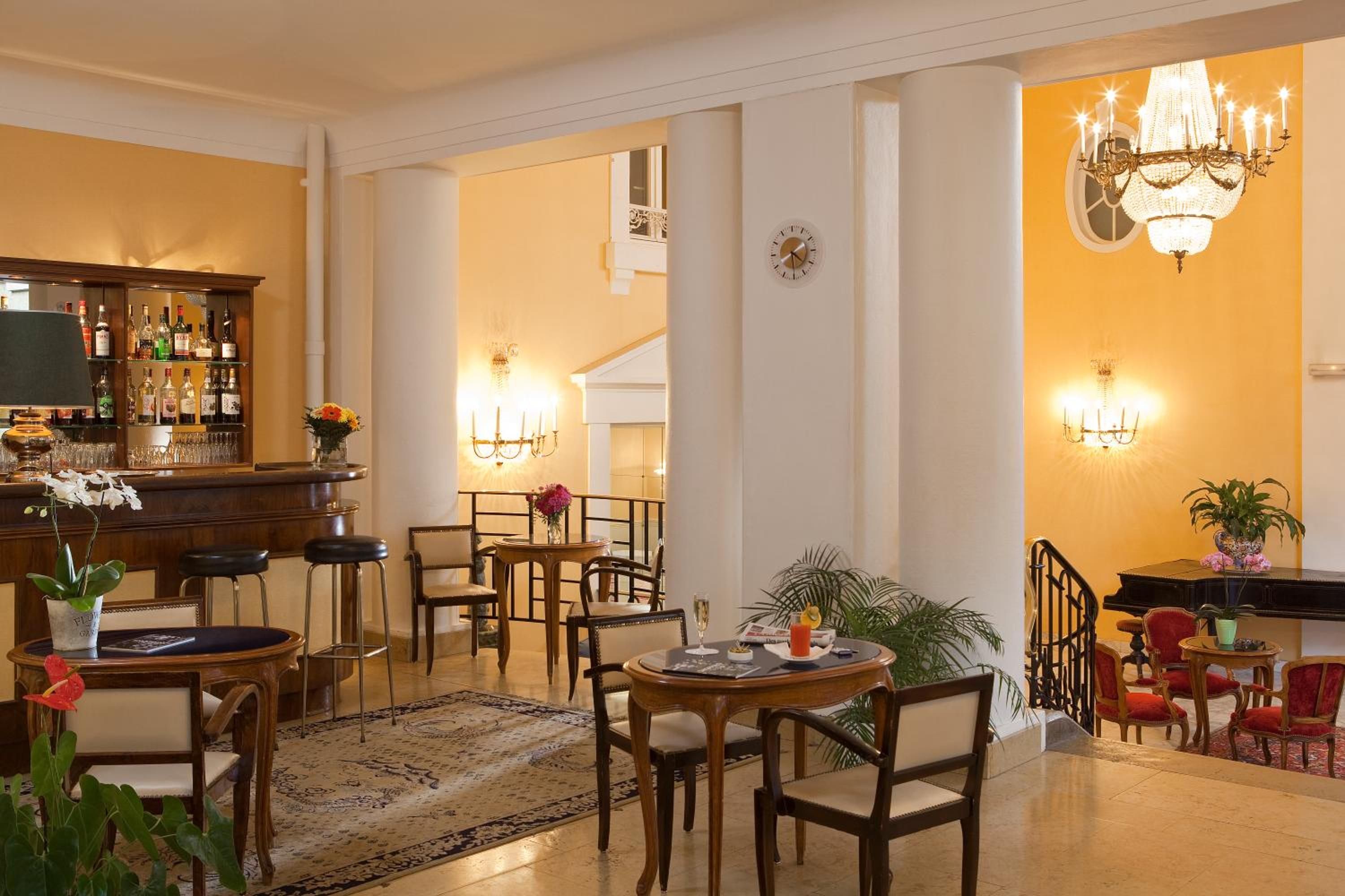 Un hall de hotel con zona de bar, asientos y una escalera.