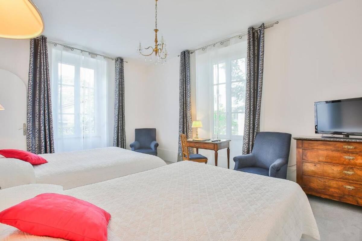 Una habitación de hotel con dos camas, televisión, escritorio y una silla.