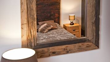 Une table de chevet en bois, avec une lampe, un miroir et une petite horloge.