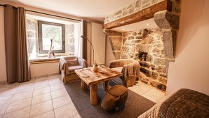 A cozy living room with a stone fireplace, a wooden coffee table, and a comfortable seating area. - Les Granges de Bigose (Rimeize)