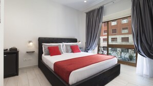 A modern bedroom with a large bed, a nightstand, a dresser, and a view of the city through a balcony. - Suite Dei Catalani (Naples)