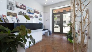 A reception area with a counter, framed pictures on the wall, and potted plants. - Suite Dei Catalani (Naples)