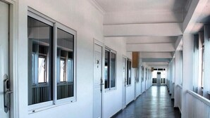 A long, narrow hallway with white walls and dark flooring, leading to a distant door at the end. - PSB Guest House (Accra)