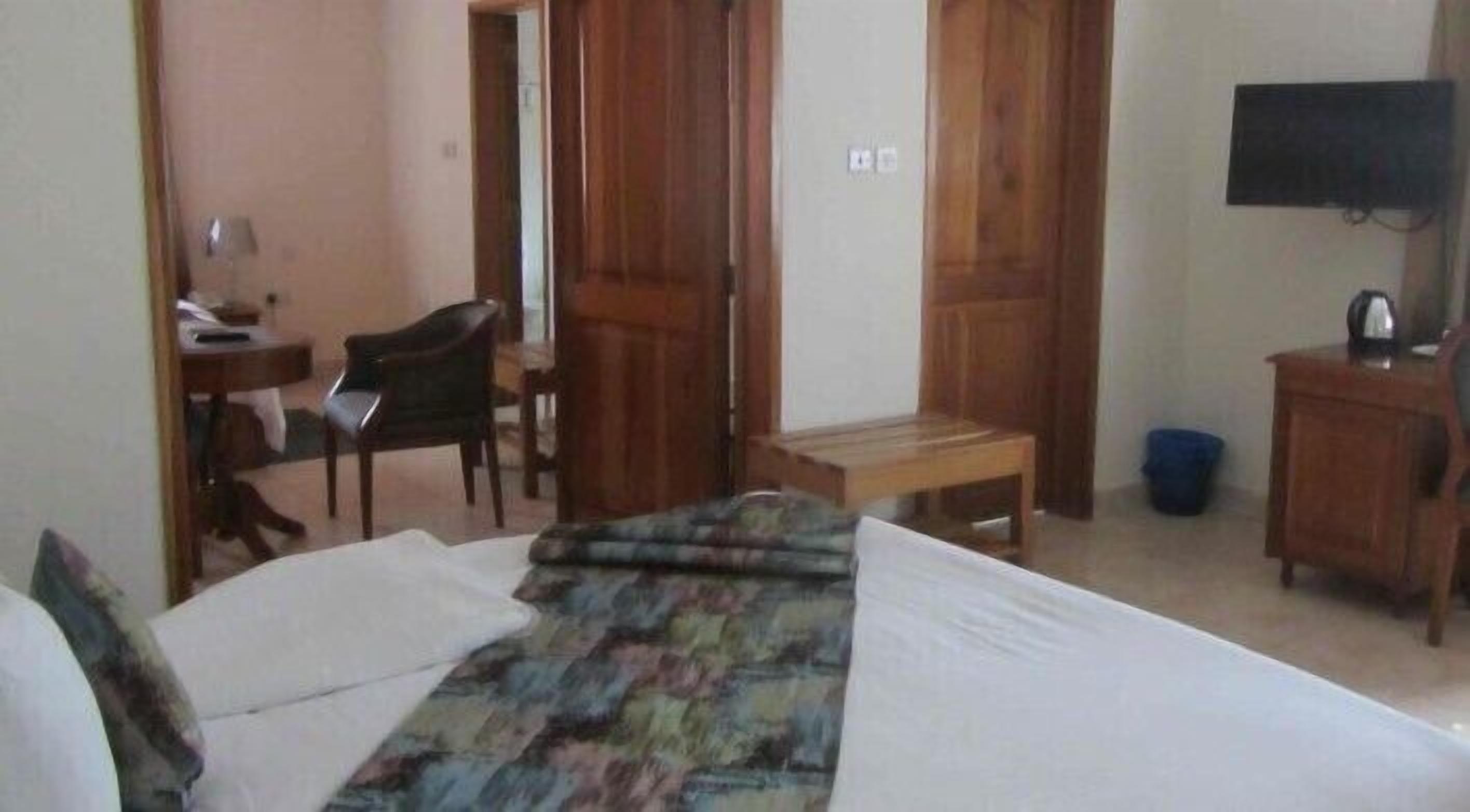A hotel room with a bed, a desk, a chair, and a television.