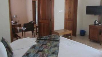 A hotel room with a bed, a desk, a chair, and a television.