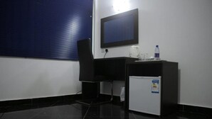 A small office space with a desk, chair, and a refrigerator. - PSB Guest House (Accra)