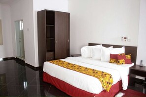 A hotel room with a large bed, a wardrobe, and a bedside table. - PSB Guest House (Accra)