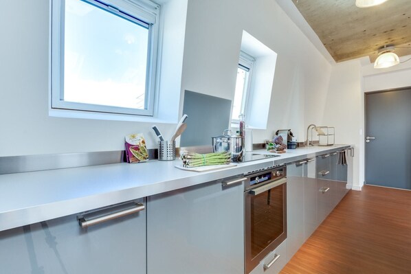 A modern kitchen with stainless steel appliances, a wooden countertop, and a window providing natural light. - Sweett | Milan VI - Four Bedroom Apartment, Sleeps 10 (Paris)