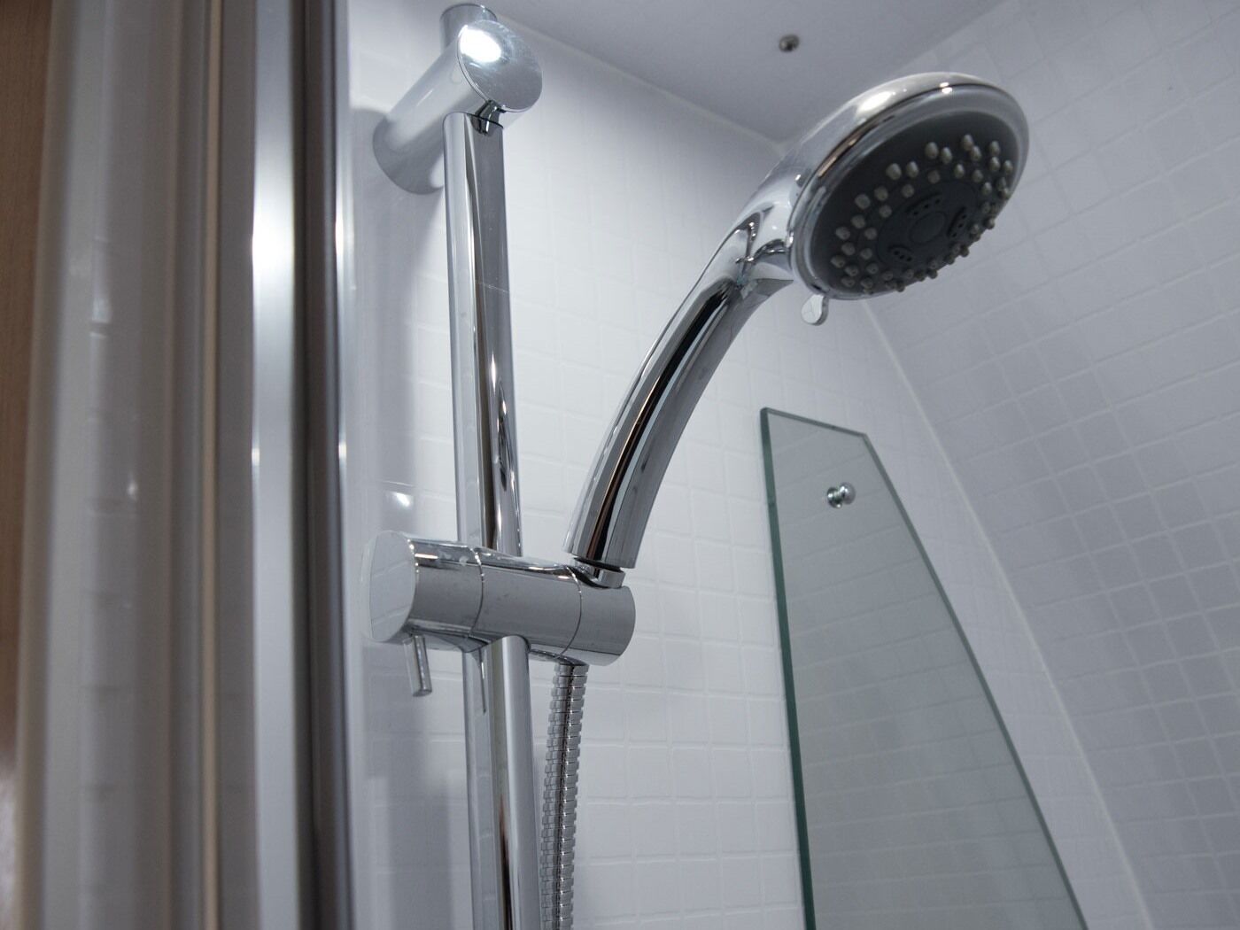 A modern shower with a handheld showerhead and a fixed rain showerhead.