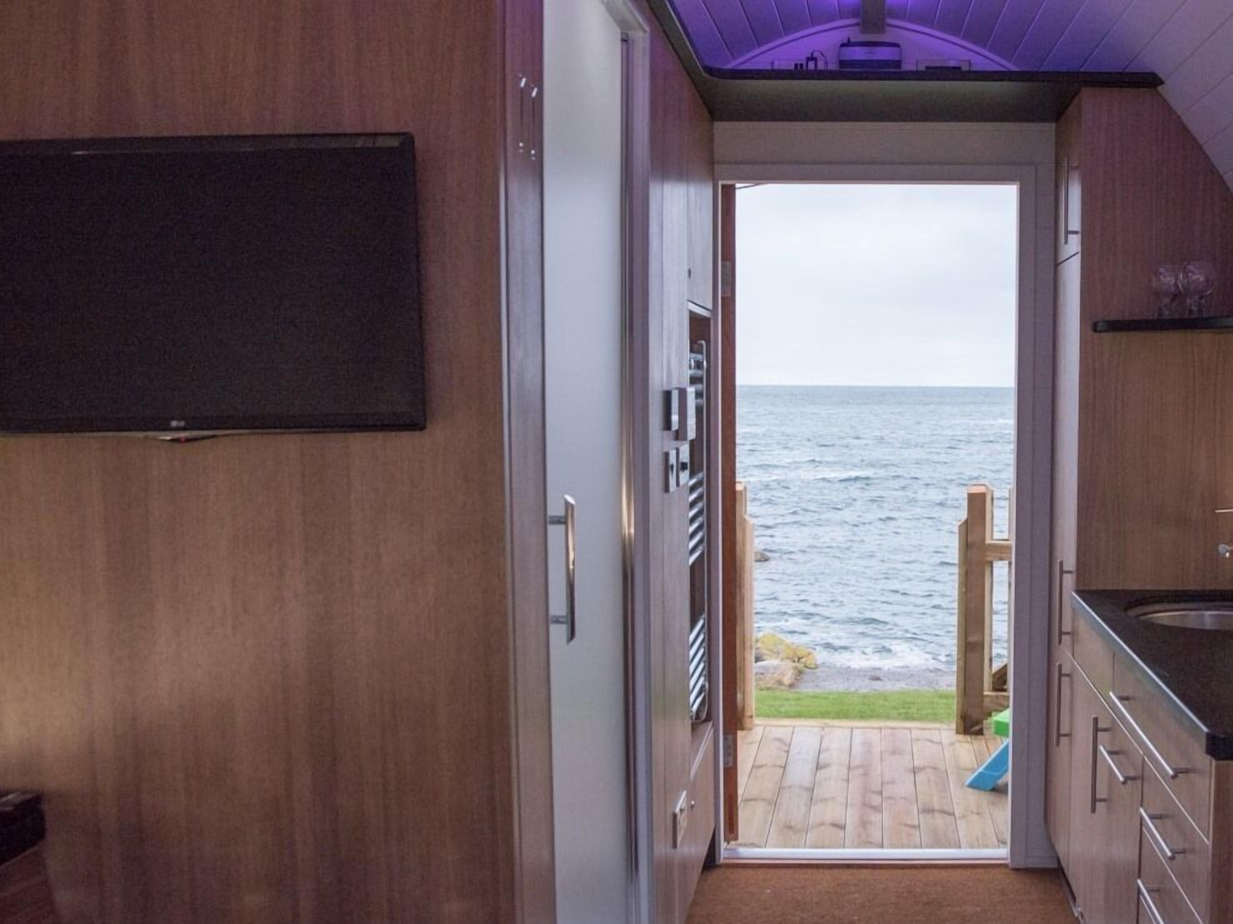 Una cucina compatta con vista sul mare attraverso una porta aperta.