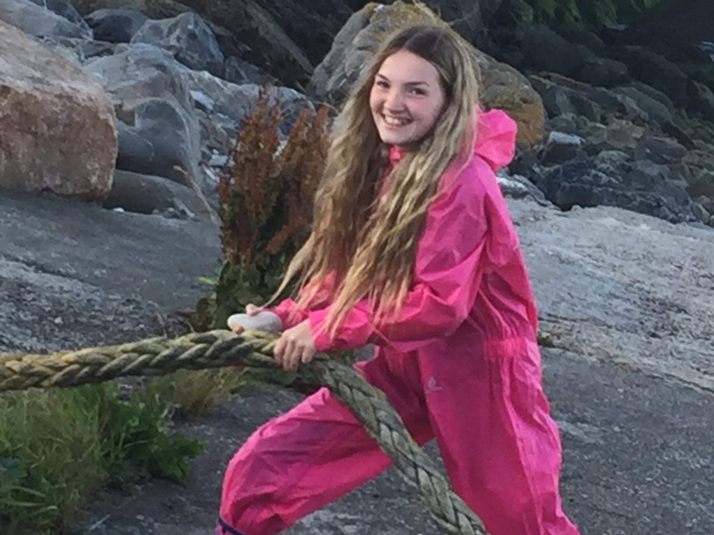 A person in a pink raincoat pulling a rope.