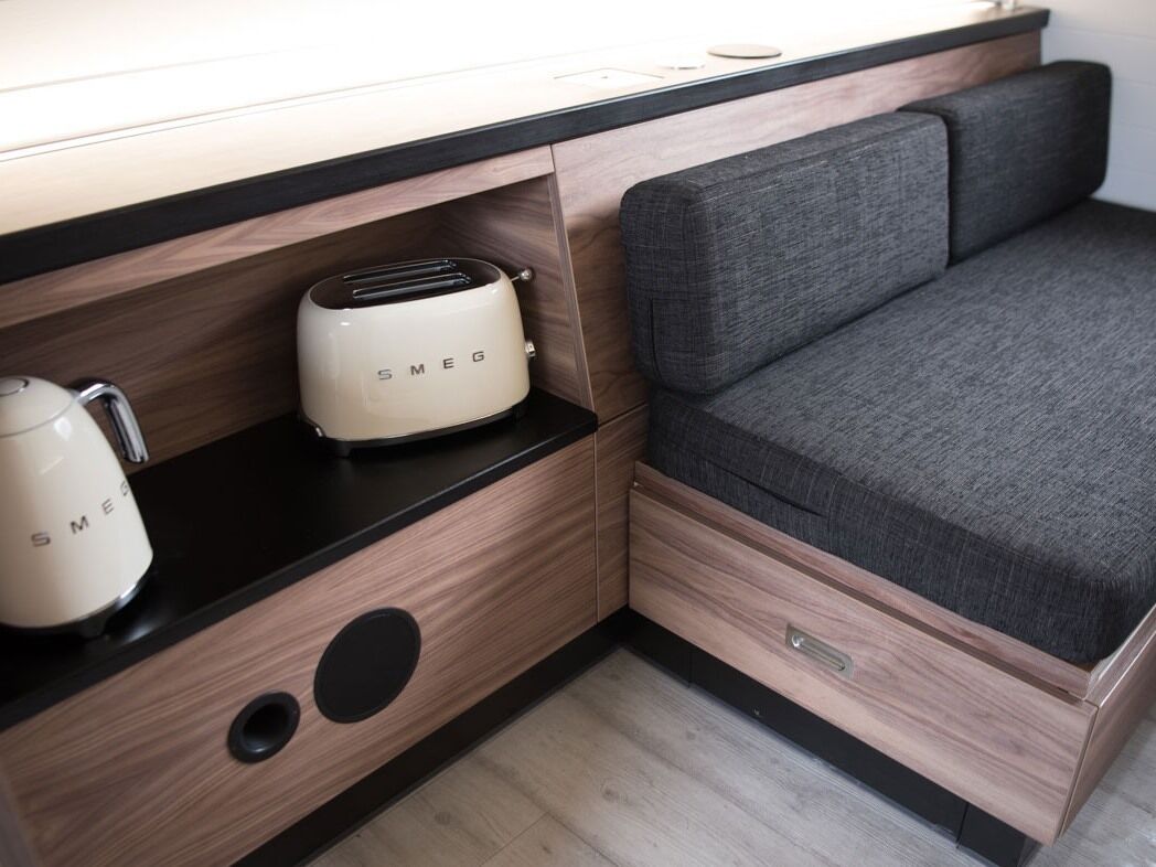 A compact kitchenette with a toaster, a kettle, and a drawer unit.