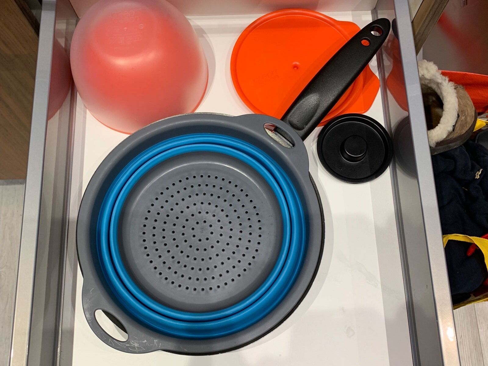 Un cajón de cocina con un colador, una tapa de olla y un globo.