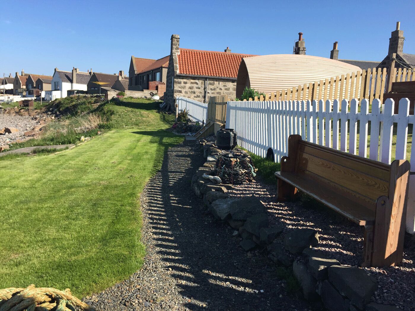 A well-maintained garden pathway leading to a stone building with a white picket fence.
