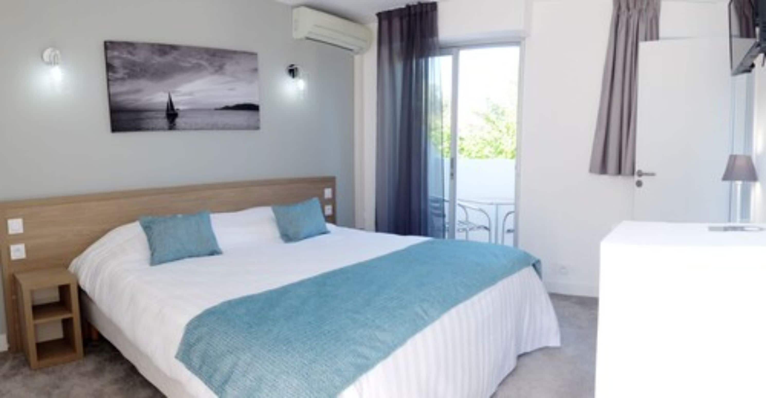 Une chambre à coucher comprenant un lit, une table de chevet, une commode, une fenêtre avec des rideaux et un climatiseur fixé au mur.