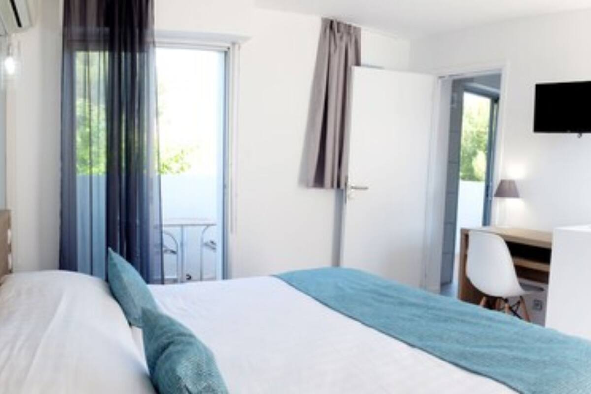 Een hotelkamer met een bed, een bureau, een stoel, een televisie en een raam met gordijnen.
