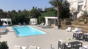 Ein Pool mit Liegestühlen und einer überdachten Sitzgruppe.