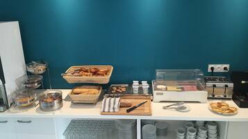 Buffet de l'esmorzar amb diverses plats i utensilis.