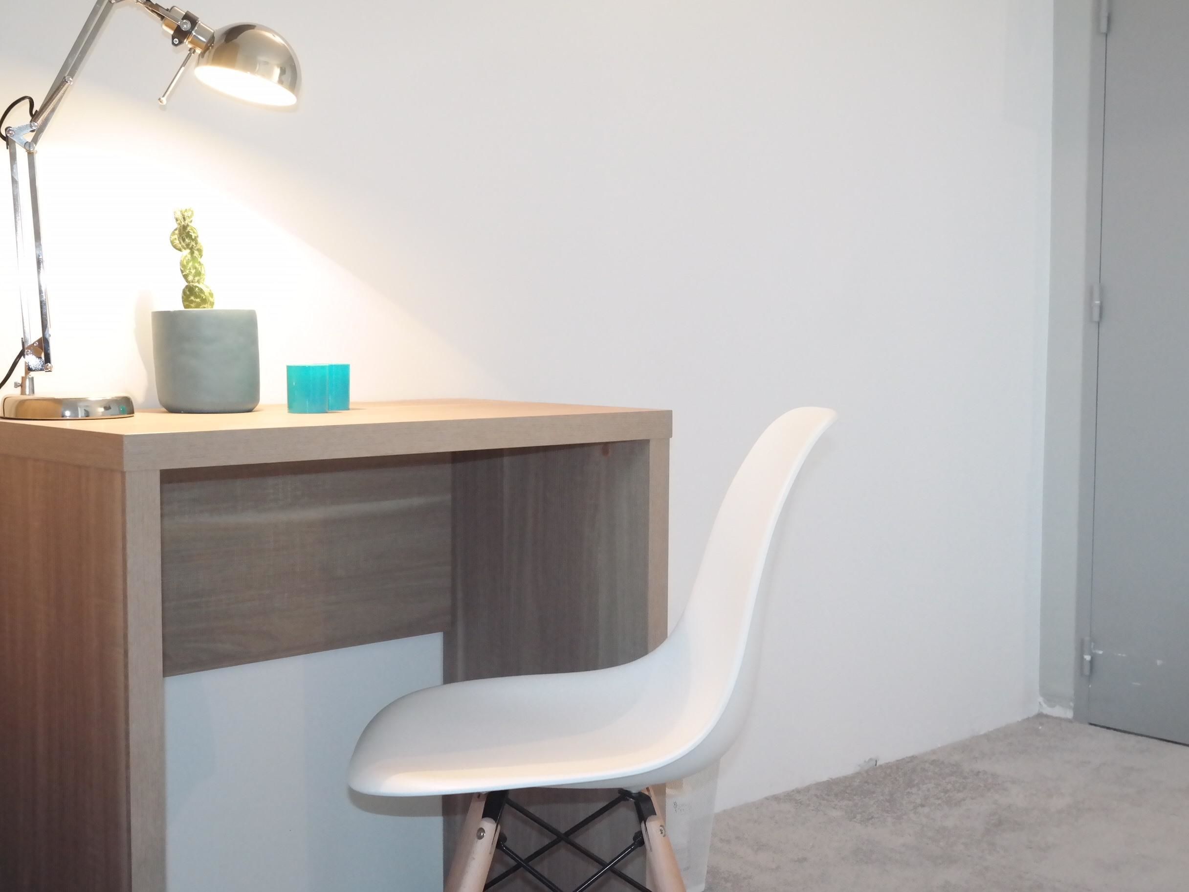 A workspace with a desk, chair, lamp, and decorative items.