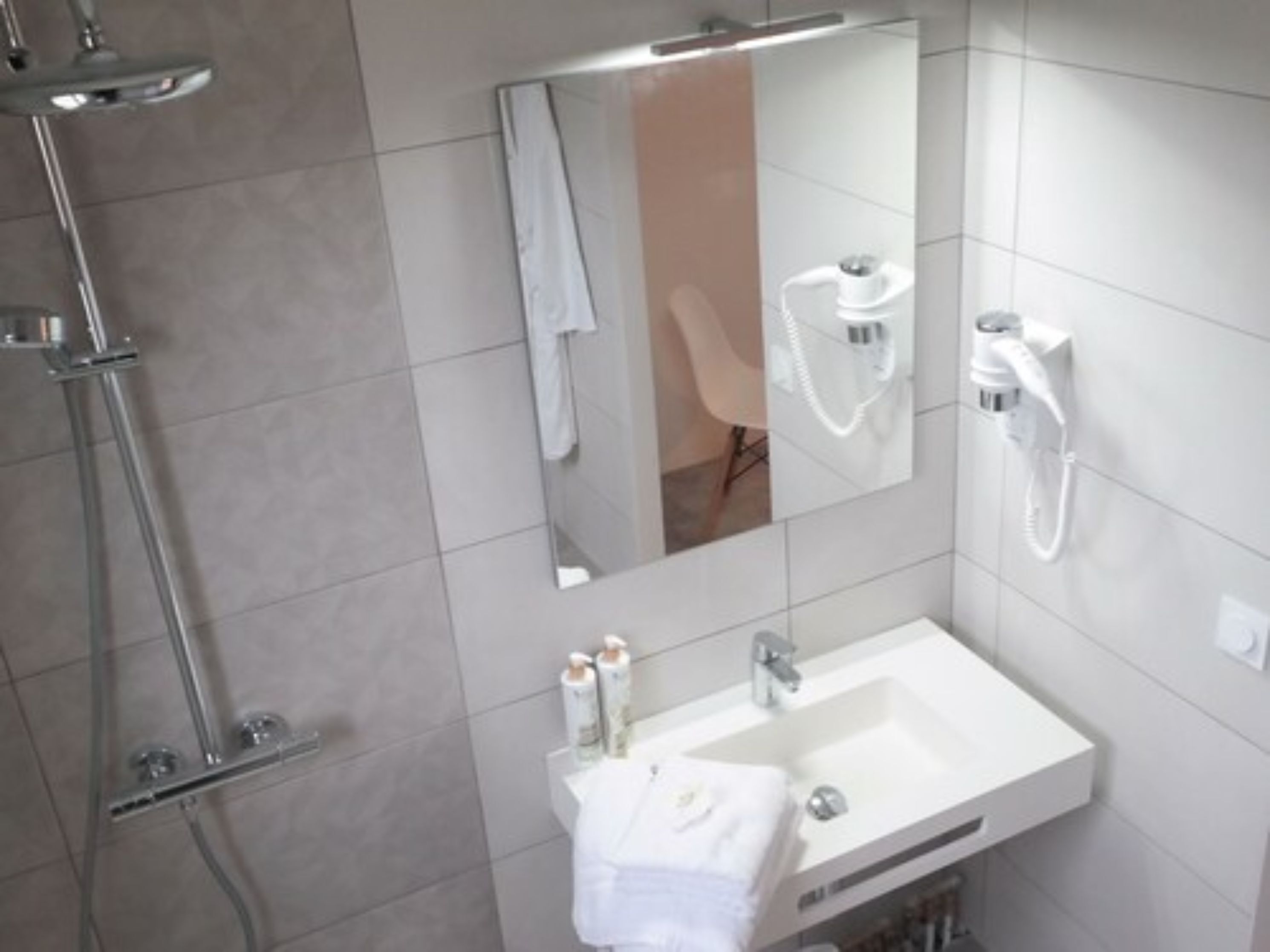 A modern bathroom with a shower, a sink, and a mirror.