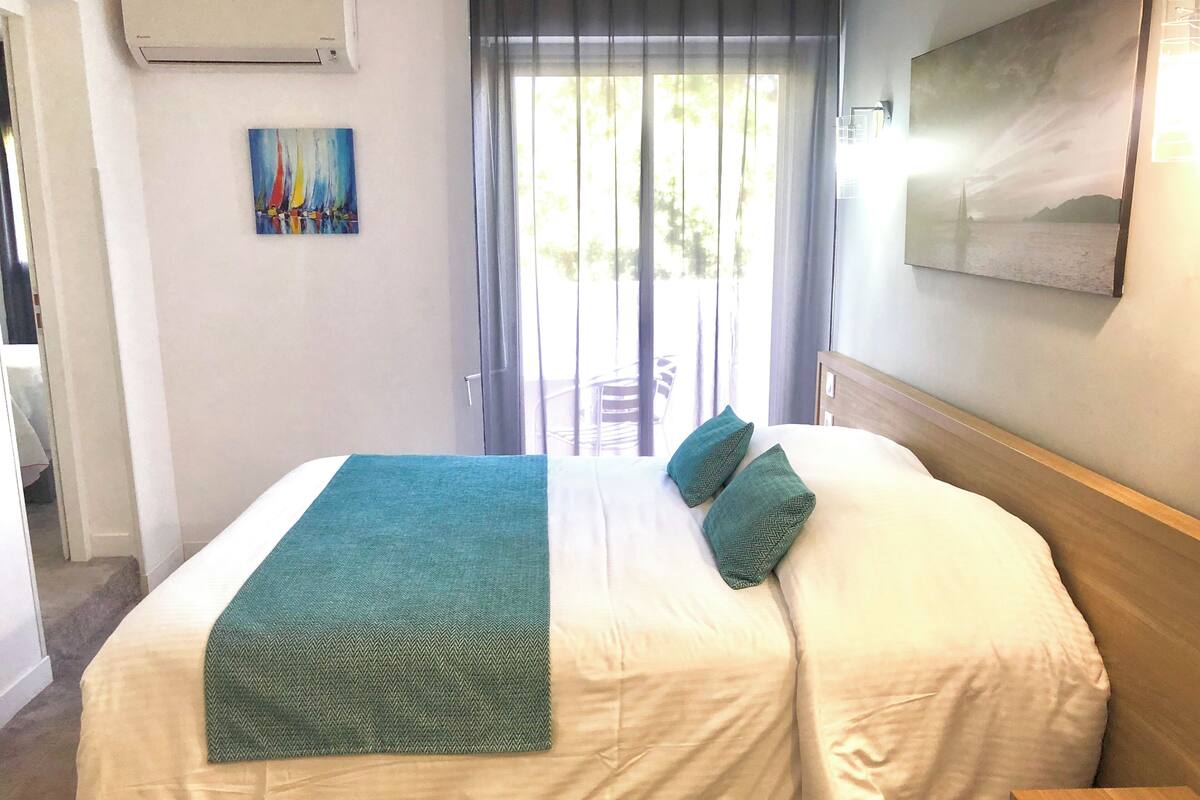 Een hotelkamer met een bed, een schilderij aan de muur en een raam met gordijnen.