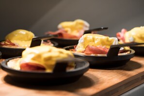 A close-up of a breakfast dish with eggs benedict, ham, and hollandaise sauce. - The Jacquard, Autograph Collection (Denver)