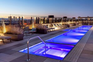 A rooftop pool area with lounge chairs and a city skyline view. - The Jacquard, Autograph Collection (Denver)