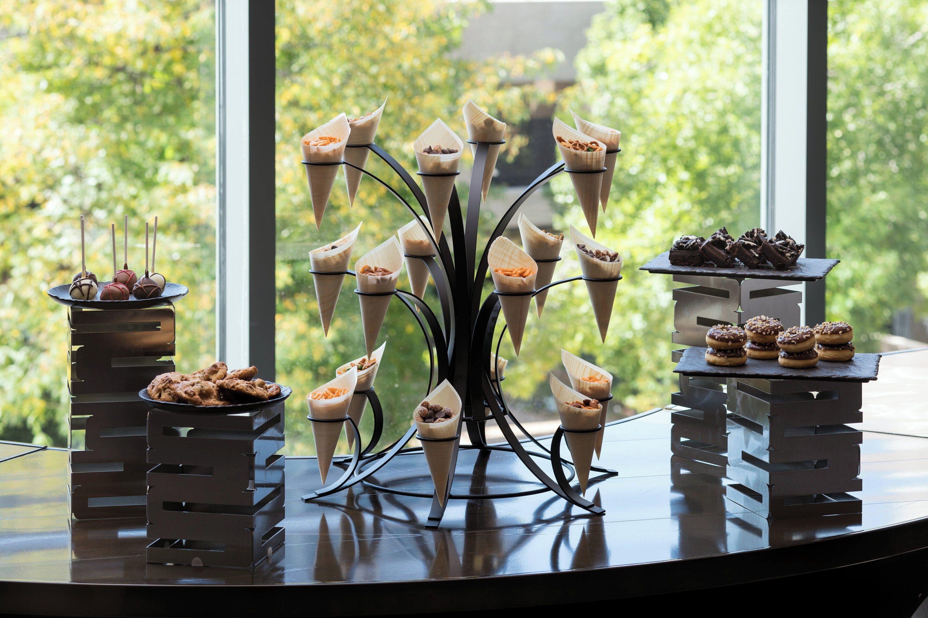 A dessert display with various confections on a table near a window.