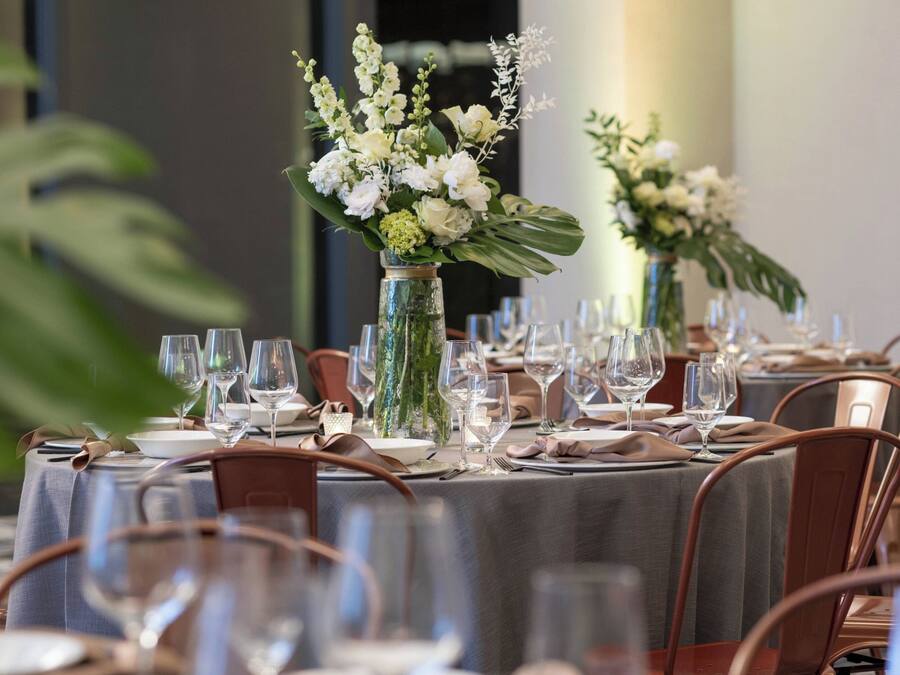 A dining table set with multiple wine glasses, plates, and cutlery, surrounded by chairs.