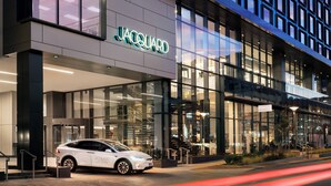 Un bâtiment moderne avec une façade en verre et une voiture blanche garée devant.