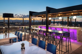 Enjoy panoramic city views from our rooftop bar, featuring a spacious seating area with bar stools and tables. at The Jacquard, Autograph Collection