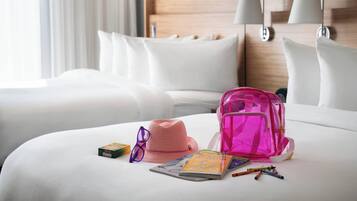 Una cama bien hecha con una mochila rosa, un sombrero, algunos libros y material de escritorio sobre ella.
