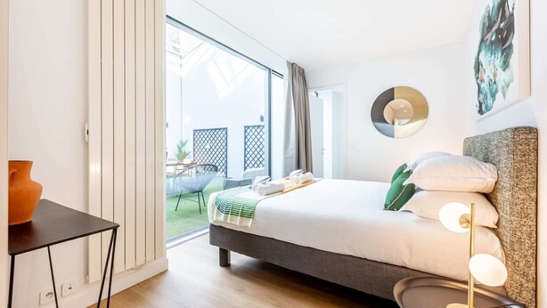 A modern bedroom with a bed, bedside table, and a view of the outdoor area. - Sweett | Brune II - Four Bedroom Apartment, Sleeps 10 (Paris)