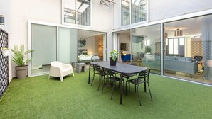 A modern outdoor patio with a dining table and chairs, surrounded by glass doors and windows. - Sweett | Brune II - Four Bedroom Apartment, Sleeps 10 (Paris)