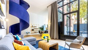 A modern living room with a grey sofa, a yellow armchair, and a blue spiral wall feature. - Sweett | Brune VI - Three Bedroom Apartment, Sleeps 8 (Paris)