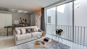 A modern living room with a sofa, coffee table, and a dining area with a kitchen counter.