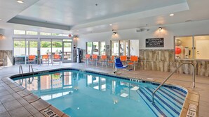 Une piscine à l’eau d’un bleu cristallin, entourée de chaises orange et dotée d’un poste de surveillance pour les sauveteurs.